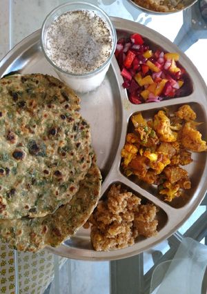 A picture of Methi paranthe with chaas aalu Gobhi sabji, salad and halwa.