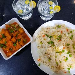 A picture of Chicken manchurian and egg vegetable fried rice with fresh lime.