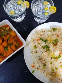 A picture of Chicken manchurian and egg vegetable fried rice with fresh lime.