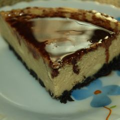 A picture of Coffee and rum flavored Cheesecake with an Oreo Crust and chocolate sauce topping.