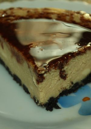 A picture of Coffee and rum flavored Cheesecake with an Oreo Crust and chocolate sauce topping.