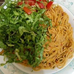 A picture of Spaghetti Jollof with lettuce and tomato.