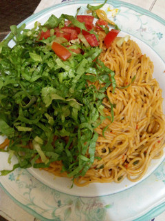 A picture of Spaghetti Jollof with lettuce and tomato.