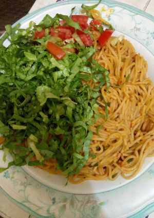 A picture of Spaghetti Jollof with lettuce and tomato.