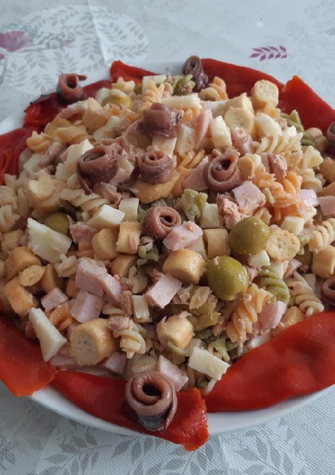 Una foto de Ensalada de hélices de color con piquillo y anchoas