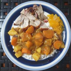 A picture of Japanese curry rice with roast pork and pickle radish on rice.