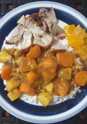 A picture of Japanese curry rice with roast pork and pickle radish on rice.