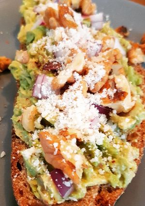 Une photo de Avocado toast avec oignon rouge, des noix et un peu de parmesan