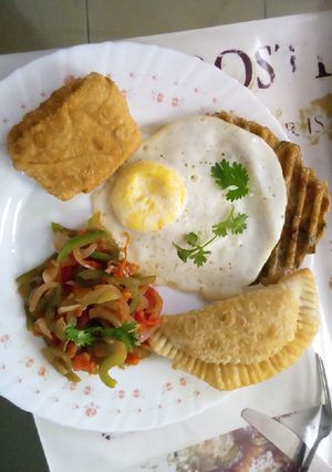 A picture of Poached eggs,samosa,hash browns and kachumbari.