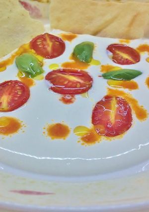 Foto di Crema di burrata, datterini confit, salsa di datterini a crudo e pane carasau