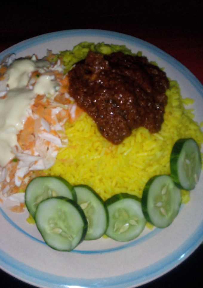 A picture of Curry Rice and stew, Garnished with cucumber and salad.