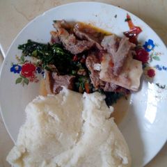 A picture of Beef stew with greens and ugali.