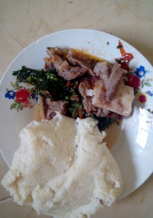 A picture of Beef stew with greens and ugali.