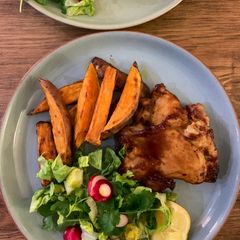 A picture of Sticky bbq chicken thighs served with sweet potato chips and a crisp lemon salad.