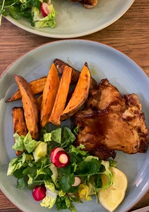 A picture of Sticky bbq chicken thighs served with sweet potato chips and a crisp lemon salad.