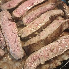 A picture of Flank Steak on a bed of Onions.