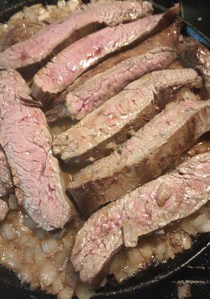 A picture of Flank Steak on a bed of Onions.