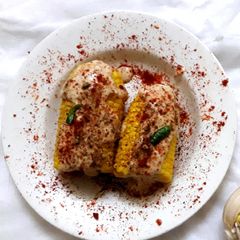 A picture of Corn on the cob in cheese sauce.