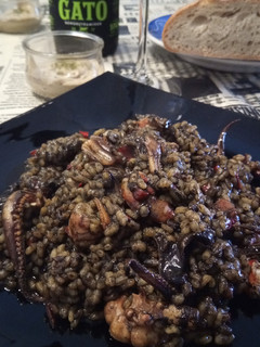 Una foto de Arroz negro a la paella con calamares de potera, gambones y alioli de dos ajos
