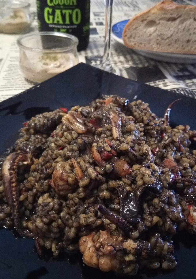 Una foto de Arroz negro a la paella con calamares de potera, gambones y alioli de dos ajos
