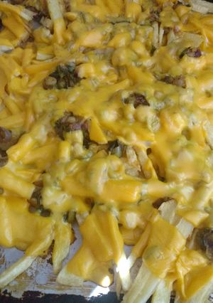 Una foto de Papas fritas con queso cheddar y cebolla de verdeo