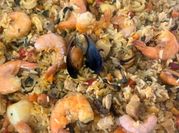 Una foto de paella de carne y mariscos