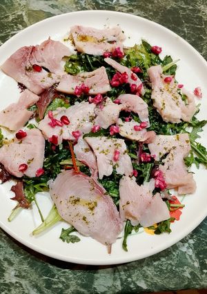 A picture of Swordfish Carpaccio with Arugula and Pomegranate Seeds.