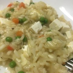 A picture of Vegetable risotto with cubed cheese.