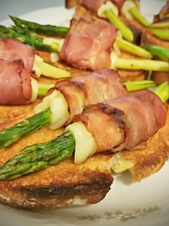 Una foto de Tostas con espárragos envueltos en bacon y queso fundido