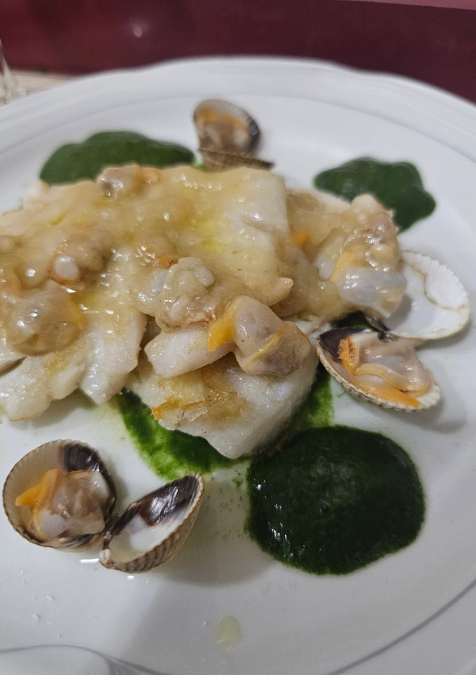 Una foto de Merluza con salsa de berberechos y culis de espinacas con espuma