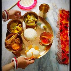 A picture of Bengali thali mutton kosa with plain rice, vegetable curry,alu posto,rasogolla and chutney.