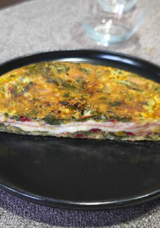 Una foto de Tortilla de acelgas rojas rellena de jamón y queso