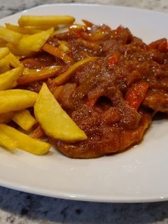 Una foto de Filetes de cerdo en salsa de tomate y pimientos con patatas