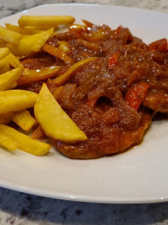Una foto de Filetes de cerdo en salsa de tomate y pimientos con patatas