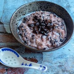 A picture of Sweet black sticky rice pudding with nutty black beans in coconut syrup.