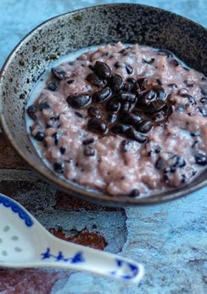 A picture of Sweet black sticky rice pudding with nutty black beans in coconut syrup.