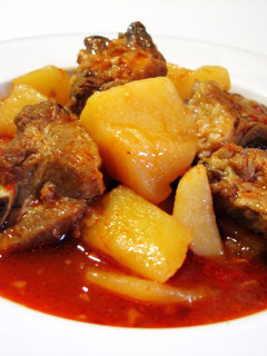 Una foto de costillas con patatas guisadas