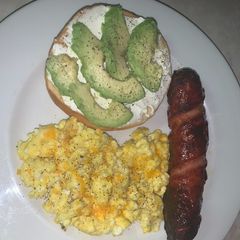 A picture of Avocado bagel with cheesy eggs and pineapple smoked sausage.
