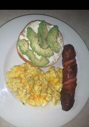 A picture of Avocado bagel with cheesy eggs and pineapple smoked sausage.
