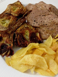 Una foto de Presa ibérica a la plancha con alcachofas y patatas fritas