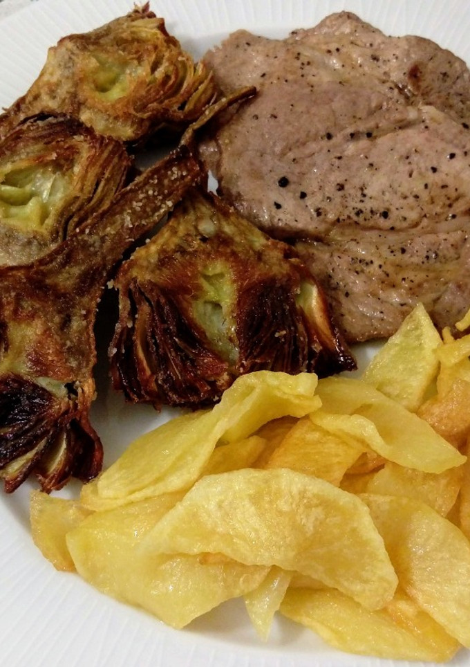 Una foto de Presa ibérica a la plancha con alcachofas y patatas fritas
