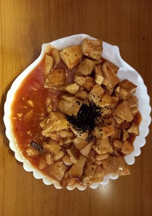 A picture of Teriyaki marinated tofu in tomato-ananas-bamboo shoot sauce with white beans and kalonji (vegan).