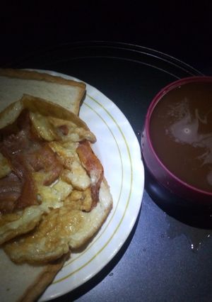 A picture of Fried bacon and egg with hot drinking chocolate.