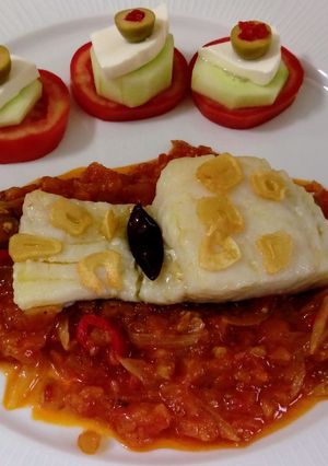 Una foto de Bacalao al ajillo con salsa de tomate y pinchitos de tomate
