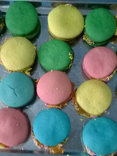 Una foto de Alfajores de maicena de varios colores rellenos con mermelada