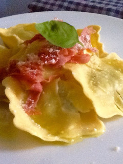 Una foto de Raviolis de ricotta, queso de cabra y rúcula con proscciutto y granna padano