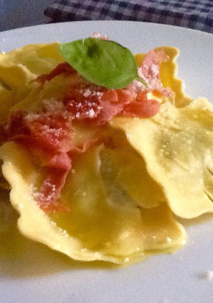 Una foto de Raviolis de ricotta, queso de cabra y rúcula con proscciutto y granna padano