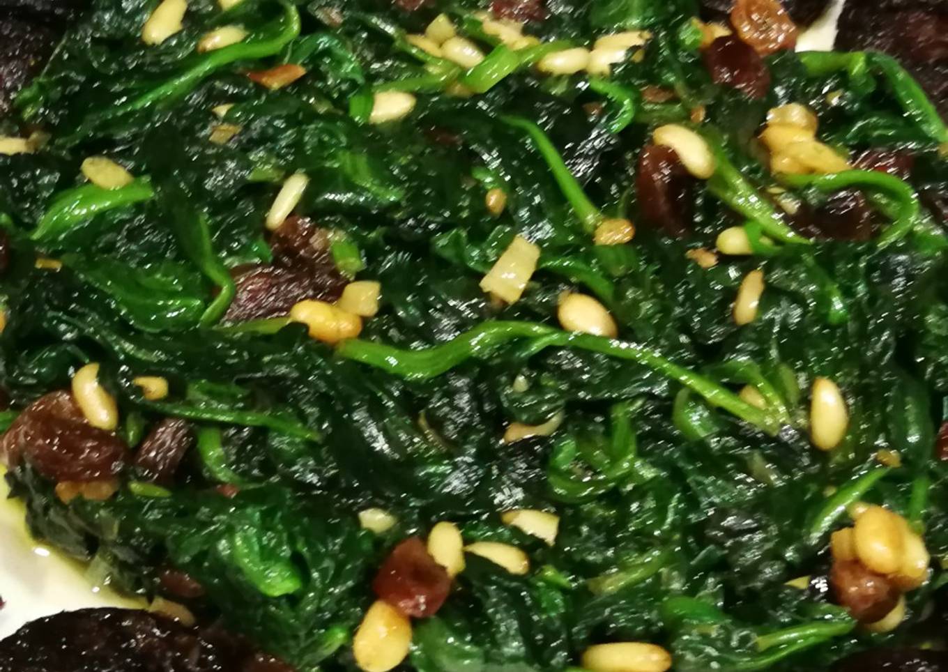 Espinaca fresca con lluvia de piñones y uvas pasas