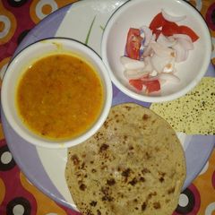 A picture of Yellow dal (moong dholi) with chappati and salad.