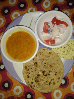 A picture of Yellow dal (moong dholi) with chappati and salad.